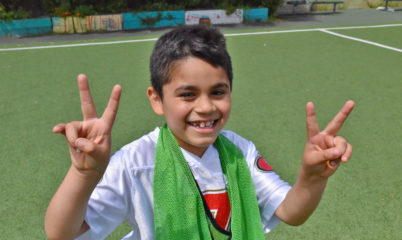 kid smiling and holding up peace signs