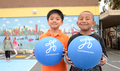 two kids holding kickballs